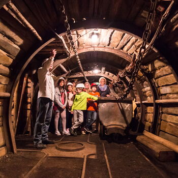 Die Gruppe einer Geopark-Schule, die in einem Tunnel des Bergwerks steht. Mittendrin steht ein Wagon, der früher zum Abtransport der Kohle diente.