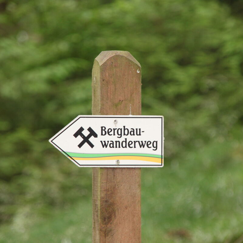 Ein Schild mit "Bergbauwanderweg" beschriftet zeigt die Laufrichtung an.