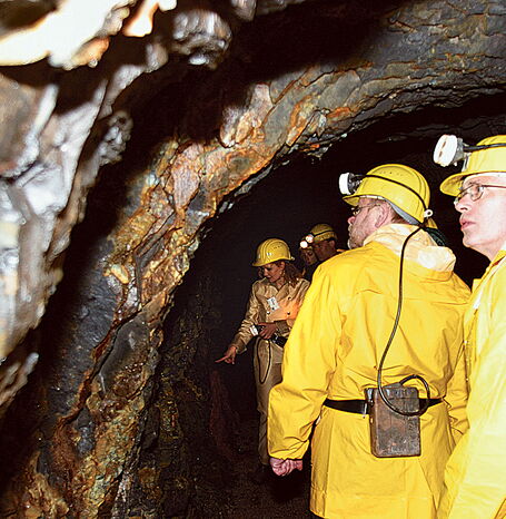 Besuchergruppe im Stollen bewundert die gold-schimmernden Wände.
