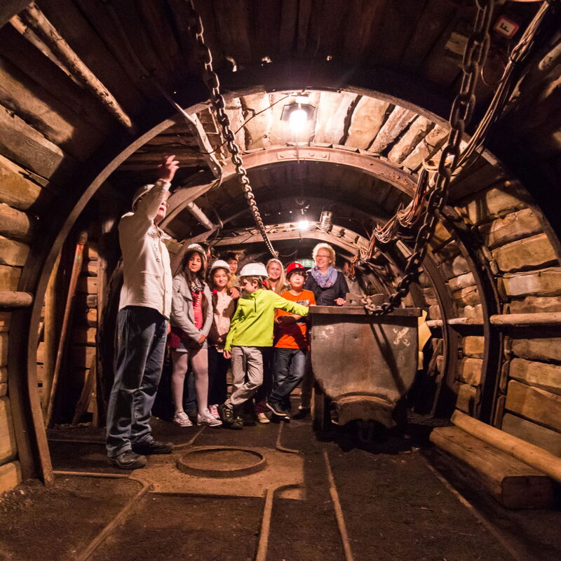 Die Gruppe einer Geopark-Schule, die in einem Tunnel des Bergwerks steht. Mittendrin steht ein Wagon, der früher zum Abtransport der Kohle diente.