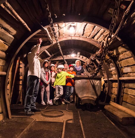 Die Gruppe einer Geopark-Schule, die in einem Tunnel des Bergwerks steht. Mittendrin steht ein Wagon, der früher zum Abtransport der Kohle diente.